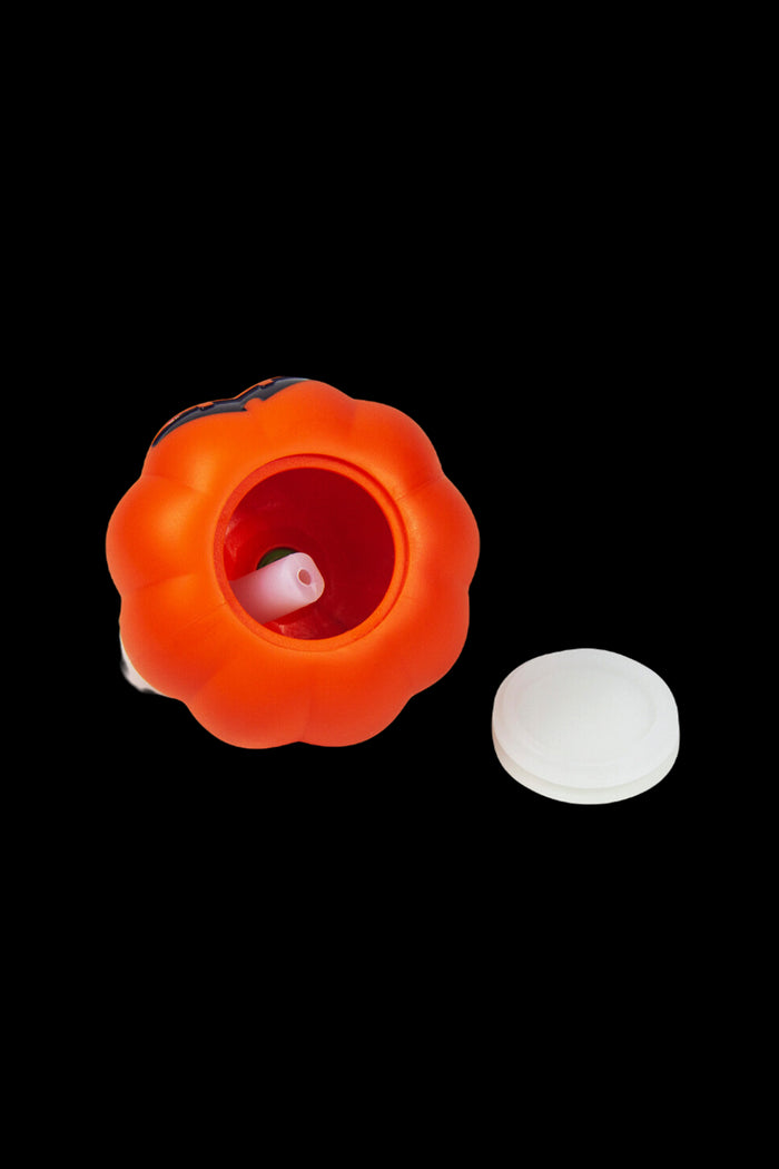 Orange pumpkin-shaped smoking pipe with a white screen nearby.