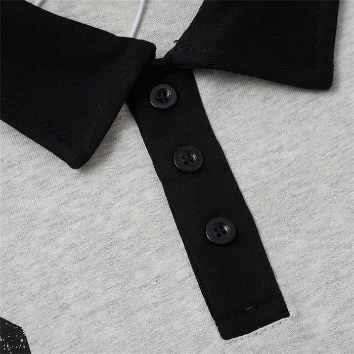 Detail of the gray polo shirt showing its black three-button placket and textured knit surface