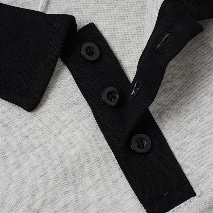 Close-up of the partially open black button placket with three buttons and collar stitching