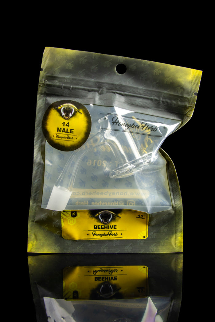 A sealed, clear plastic bag of cannabis, branded “Honeybee Herbs,” with a reflective surface showing its mirrored image.