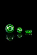 Green glass marbles with swirling patterns, reflecting on a black surface.
