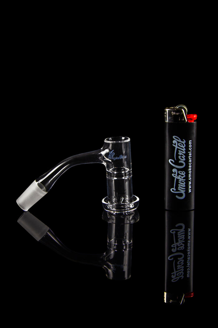 Glass oil rig with a quartz banger and butane torch on a reflective black surface.