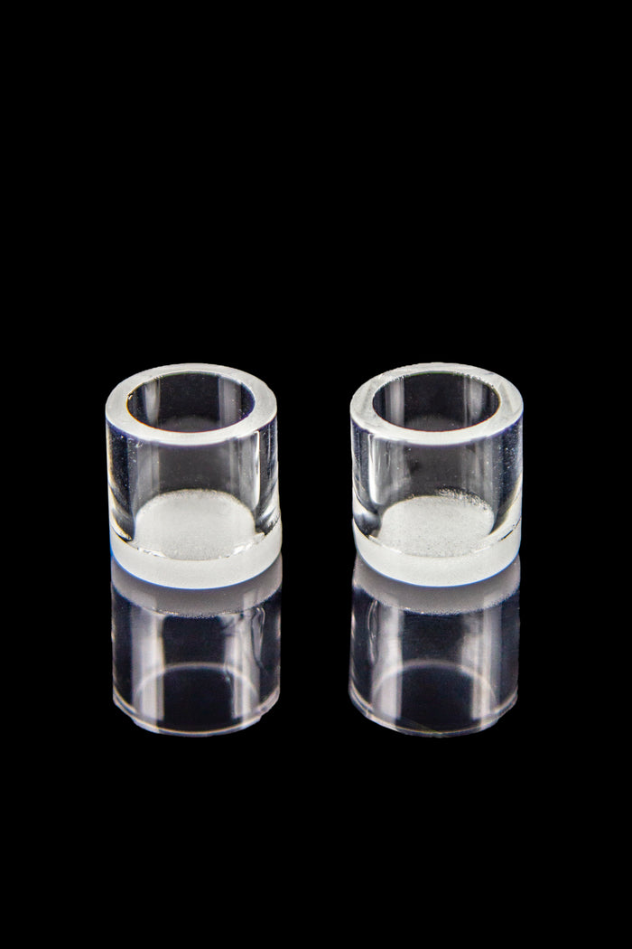 Clear quartz bongs with residual cannabis concentrate visible inside, isolated on black.