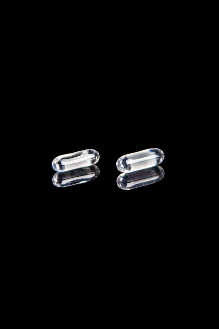 Clear glass cannabis capsules against a black background.