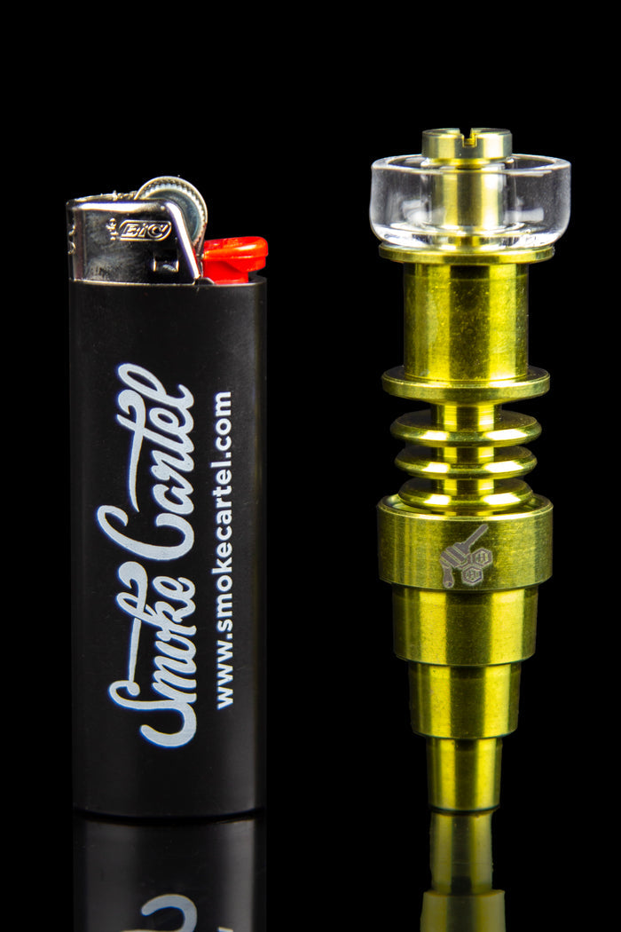 Gold cannabis dab rig with a clear glass bowl next to a black lighter branded with “Smoke Cartel.”