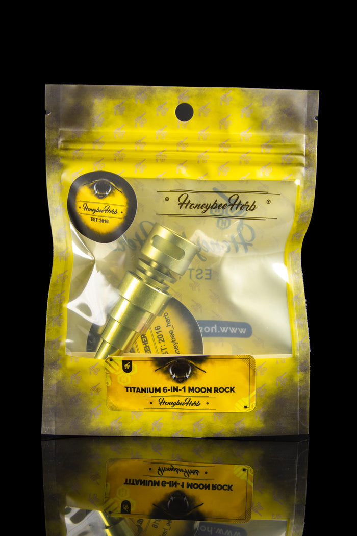 Gold mylar bag containing cannabis accessories, labeled “Honeybee Herb Titanium 6-in-1 Moon Rock.”