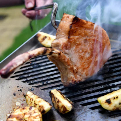 Steak being grilled with vegetables on a barbecue