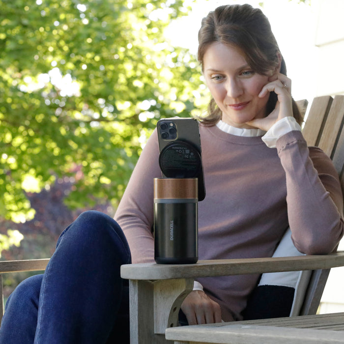Woman on her patio using the M150 charger outside to hold and charge her smartphone