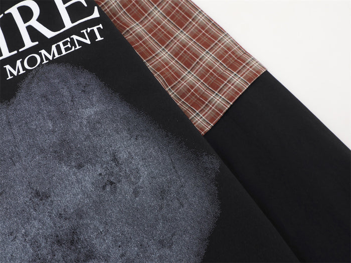Close-up of the shirt front graphic beside the seam where the red plaid sleeve meets the black sleeve panel