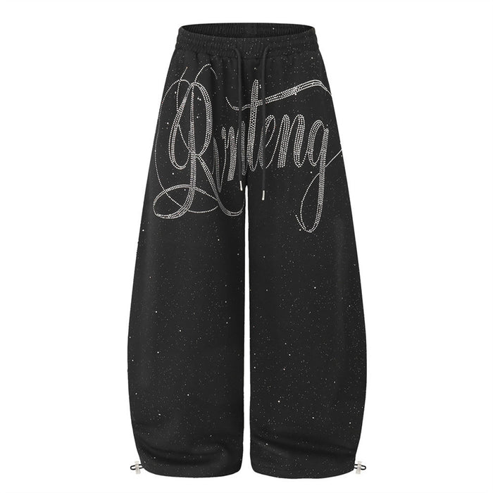 Men's wide-leg black sweatpants with rhinestone script lettering and glitter speckle fabric, elastic drawstring waist and ank
