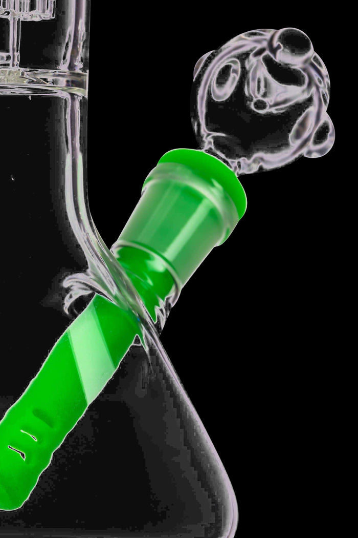 Angled close-up of a green Unbreakable Silicone Downstem inserted into a glass joint, viewed against a black background.