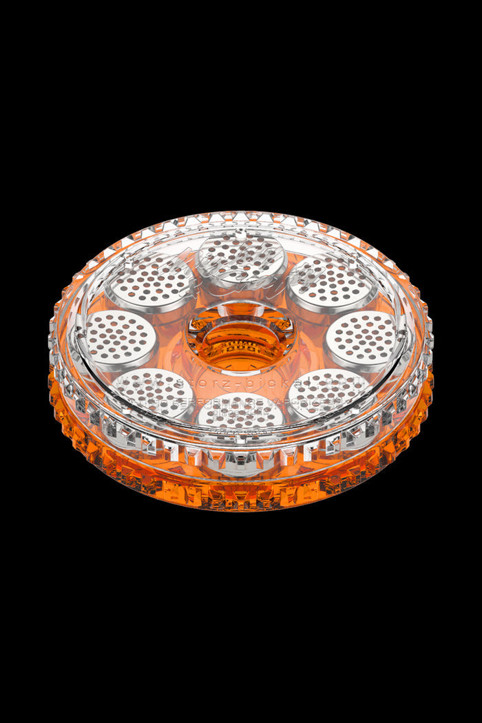 Top-down view of the clear and orange Storz & Bickel Dosing Capsules - 40 Pack arranged in a circular holder against a black background.