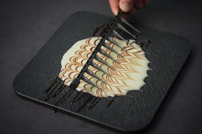Black titanium Glaze Comb with 10 teeth creating intricate design on ice cream on black plate.