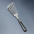 Titanium spatula with a black handle on a gray background