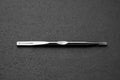 Metallic tweezer with "Titanion" branding on a textured gray background