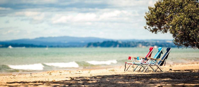 Wearever Backpack Chair royal blue red and black on beach with ocean background