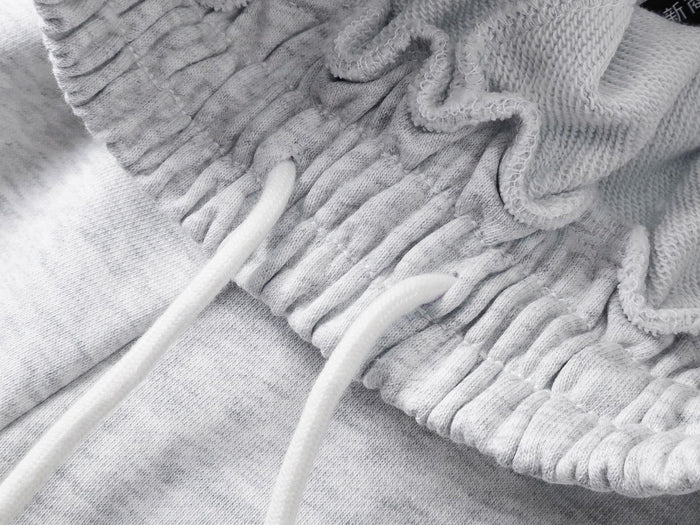 Close-up of the light gray waistband with white drawstrings and gathered knit fabric